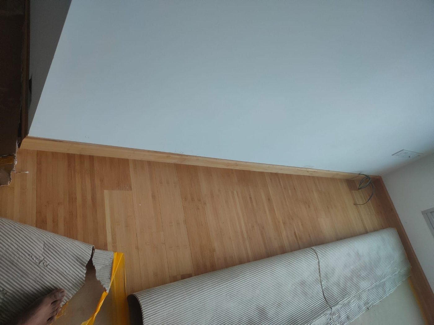 Natural bamboo plank floor in progress, showing acclimatised boards laid against a feature wall in a Singapore home