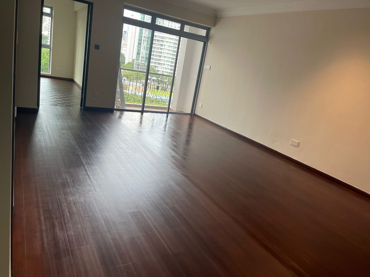 Dark-stained bamboo flooring running from a Singapore condominium living room out to a balcony with city view